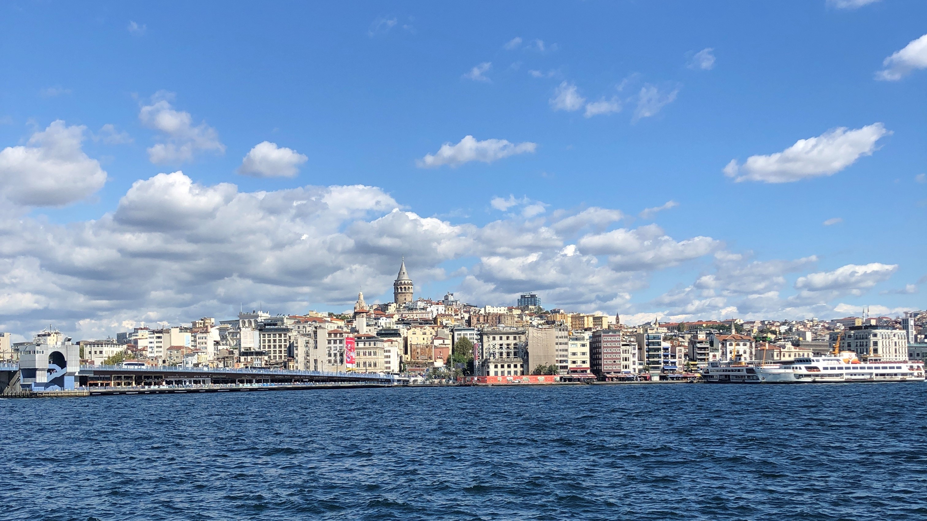 Blaues Wasser, eine Stadt von der Hafenseite mit ein paar Personenschiffen und ein leicht bewölkter Himmel