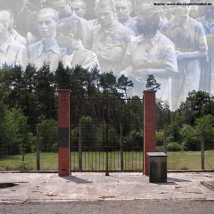 Das Bild zeigt einen ehemaligen Lagerzaun mit Tor und zwei gemauerten Pfeilern vor einer grünen Waldlandschaft der KZ-Gedenkstätte "Münchmühle". Darüber ist eine verblasste historische Aufnahme von Menschen montiert.